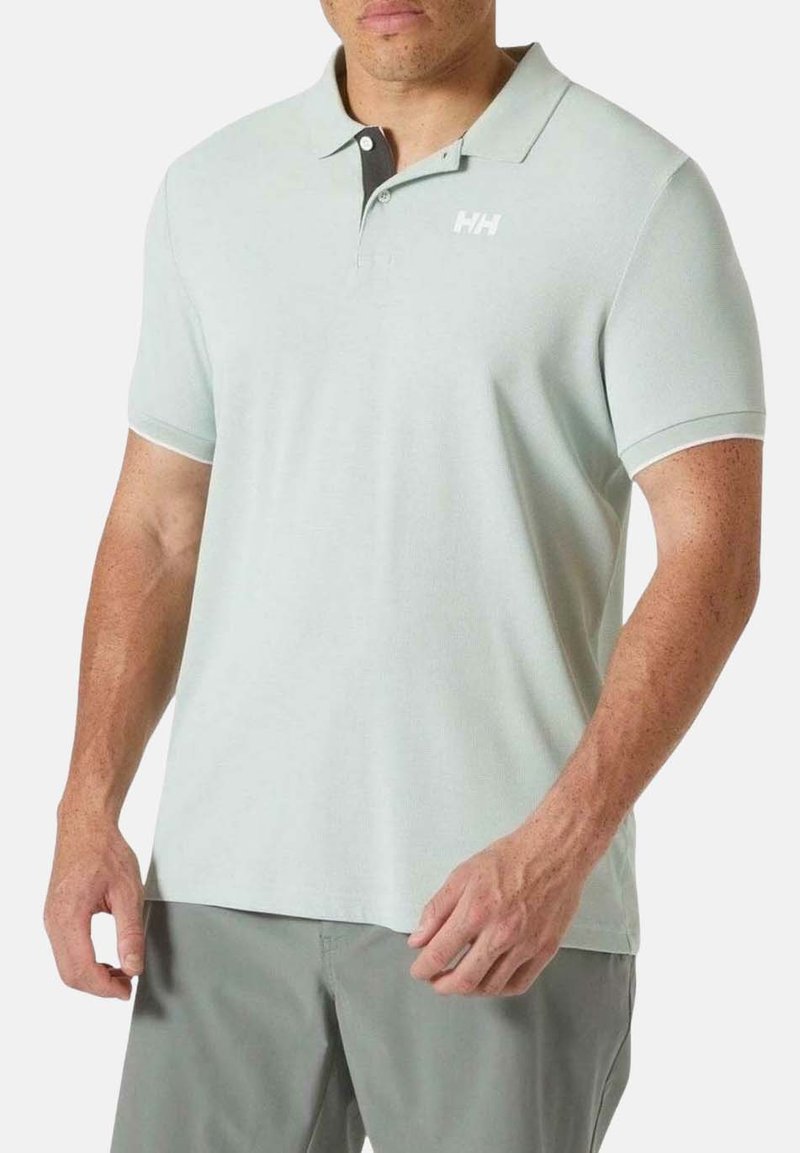 Polo de color verde claro en una tela suave, con un cuello negro y un logo blanco en el pecho. Mangas cortas y un diseño de ajuste relajado.