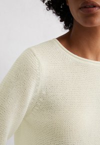 Strickpullover in hellcreme Farbe mit einer lockeren, atmungsaktiven Netzstruktur. Verfügt über einen runden Ausschnitt und subtile Nahtdetails.