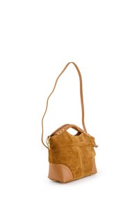 Sac à main en daim beige avec une forme structurée, comprenant une base en cuir et une bandoulière. Embelli de clous dorés et d'une poignée supérieure arrondie.