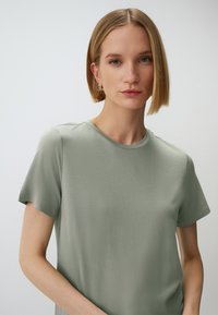 T-shirt verde chiaro a maniche corte realizzata in tessuto morbido, con scollatura rotonda e vestibilità comoda. Design semplice e senza fronzoli.