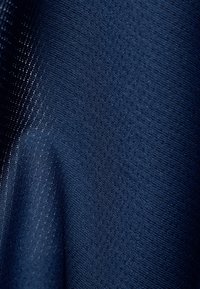 Dunkelblauer, strukturierter Stoff mit einem Muster, das kleine Löcher aufweist. Das Material scheint leicht und leicht reflektierend zu sein.