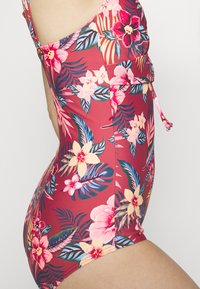 Roter einteiliger Badeanzug mit floralen Motiven, Seitenauschnitten, verstellbaren Bindebändern und einem glatten, dehnbaren Material.