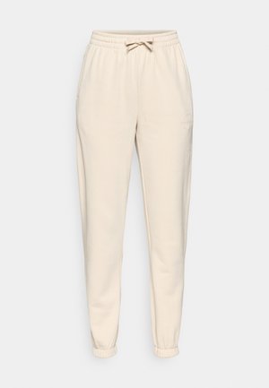 Beige sweatpants made of soft fabric, featuring an elastic waistband with a drawstring, side pockets, and elastic cuffs at the ankles.