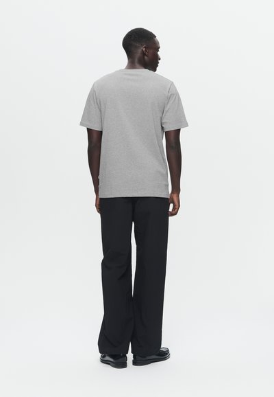 Γκρι βαμβακερό μπλουζάκι με κοντά μανίκια και στρογγυλή λαιμόκοψη, σε συνδυασμό με μαύρο, φαρδύ παντελόνι και μαύρα παπούτσια, εμφανιζόμενο από πίσω.