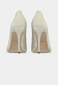 Chaussures à talons hauts en satin blanc avec un bout pointu, présentant une silhouette élégante et un talon fin, conçues pour l'élégance et les occasions formelles.