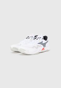 Λευκά αθλητικά παπούτσια με μαύρες λεπτομέρειες, επάνω μέρος από δίχτυ και κόκκινες λεπτομέρειες. Διαθέτουν επενδυμένη σόλα και ενσωματωμένο σύστημα κορδονιών για υποστήριξη.