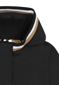 Veste noire à capuche avec une texture lisse. Comprend un col côtelé avec des rayures marron, blanches et noires. Fermeture éclair à l'avant.