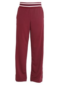 Bordowe spodnie sportowe z prążkowanym pasem z białymi i granatowymi paskami, bocznymi guzikami przy nogawkach i luźnym krojem.