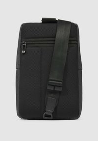 Bolso negro con tejido texturizado, que incluye un bolsillo frontal con cremallera, correa ajustable y forma rectangular. Detalles mínimos en el herraje.