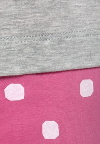 Gray fabric at the top, with a smooth texture, above bright pink fabric featuring irregular white hexagonal patterns.
