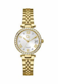 Ceas de mână din metal auriu cu un cadran rotund, un disc alb, cifre romane și o ramă accentuată cu cristale. Dispune de un afișaj pentru dată și curea din brățară.