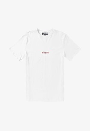 T-shirt blanc à manches courtes avec le texte "DOLCE VITA" en petits caractères rouges centrés sur le devant, étiqueté "En vacances" au niveau du col.