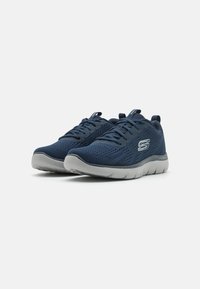 Navy blue athletic shoes with a mesh upper, lace closure, and a grey rubber sole. Features ventilation holes and brand logo on side.