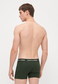 Dunkelgrüne Boxer Shorts mit einem schwarzen Bund, auf dem der Markenname "JACK & JONES" in Weiß steht. Weiches, dehnbares Material.