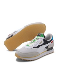 Baskets Puma blanches, noires et grises avec des accents verts, semelles en gomme naturelle et lacets blancs, montrées de côté et par le dessous.