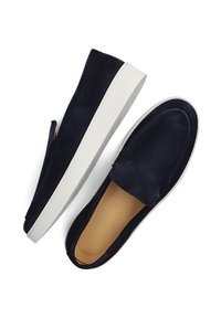 Een paar marineblauwe suede instap loafers met witte rubberen zolen en lichtbruine binnenzolen, weergegeven vanuit een boven- en zijaanzicht op een witte achtergrond.