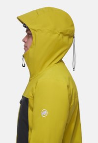 Gelbe wasserdichte Jacke mit Kapuze, schwarzen Akzenten, Reißverschlusstaschen und Logopatch am Ärmel. Glatte Textur und strukturiertes Design.