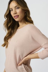 Svetlo roza oversized pulover z ribanim robom in manšetami. Mehak material, čolnasti izrez in padli ramenski dizajn.