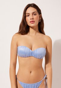 Top de bikini bandeau azul claro con textura fruncida, combinado con braguitas de bikini a juego con laterales ajustables. Tela suave y elástica.