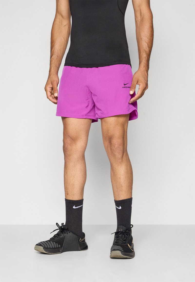 Purple Nike Pro shorts, featuring an elastic waistband, lightweight fabric, and a small black logo on the left side, paired with black athletic shoes and socks.
