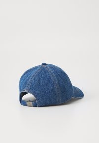 Blå denim caps med krum skygge, seks-panel design, synlige sømmer og en justerbar bakre strop med en liten hardware-detalj.
