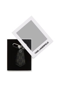 Mustriteksteime mustriga võtmehoidja karbis, millel on valge kaas, rõhutades silmapaistvat logot ja hõbedase värvusega riistvara.