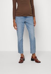 Calças de ganga azul claro com um corte reto e comprimento ligeiramente curto, combinadas com uma blusa de mangas longas castanha e mocassins castanhos brilhantes.