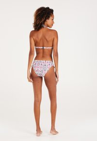Bikini komplektas, pasižymintis kaklo užrišimu ir raštuotomis kelnaitėmis. Spalvos: raudona, mėlyna ir balta, su aksesuaru ant klubų. Lygus tekstūras.