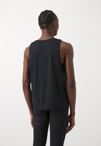Débardeur de sport noir sans manches à coupe décontractée, avec un logo subtil dans le dos, fabriqué dans un tissu léger et d'une texture douce.