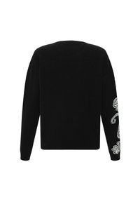 Pull noir à manches longues vu de dos avec une broderie florale blanche délicate sur la manche droite, près de l'avant-bras.