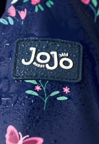 Jūrų tinklas atsparus vandeniui, su gėlių raštais, tekstūruotas logotipo pleistras su "Jojo" balta spalva, papuoštas vandens lašeliais.