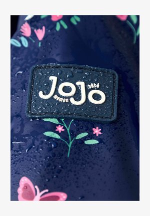 Tumed veekindel kangas, millel on lillemustrid, tekstuuriga logo-plekk valge "Jojo" kirjaga, kaunistatud veepiisadega.