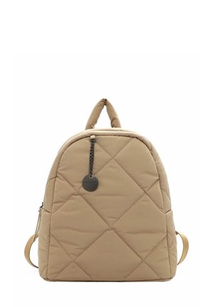 Beige Rucksack mit Steppung und runder Form, ausgestattet mit einem oberen Griff, verstellbaren Trägern und einer dekorativen Kette mit einem runden Anhänger.