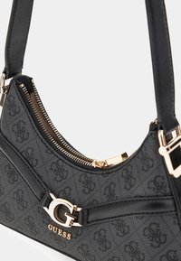 Borsa nera con motivo a logo, chiusura a zip dorata e design elegante. Presenta una maniglia regolabile e un rilievo del logo prominente sulla parte anteriore.