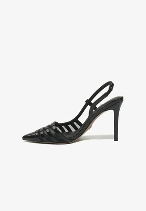 Crna salonka od lakirane kože s remenom na petu, visokom potpeticom na šiljasti vrh i vodoravne detalje na remenu, na bijeloj pozadini.