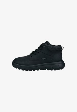 Schwarze Knöchelstiefel aus glattem Synthetikmaterial, mit einem strukturierten Bund, runder Zehenform und dicker, robuster Sohle mit sichtbaren Profilmustern.
