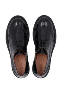 Schwarze Lederschuhe mit polierter Oberfläche, Brogue-Details und runder Zehenpartie. Mit Schnürdesign und strukturiertem Sohlen.