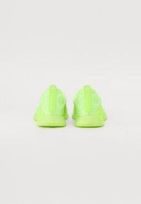 Neon green athletic shoes featuring a textured mesh upper, reinforced heel, and rubber sole. Includes a pull tab at the back for easy wear.