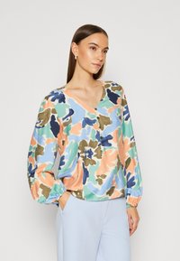 Blusa a maniche lunghe con scollo a V in un motivo floreale multicolore con tonalità di arancione, blu e verde; presenta dettagli con bottoni e polsini elasticizzati.