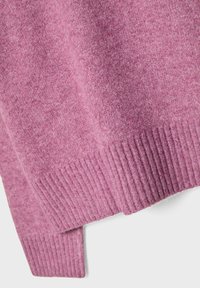 Gros plan sur un tissu tricoté rose doux avec un ourlet côtelé en bas d'un pull ou vêtement.