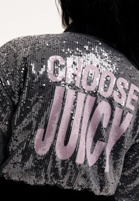 Fekete flitteres bomber dzseki, a hátán nagy rózsaszín "CHOOSE JUICY" felirattal, sima tapintású és fényes kivitelű.