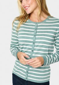 Zeleni in beli črtasti cardigan s okroglim ovratnikom, zapiranjem na gumb in dolžinami rokavov. Mehka tekstura, prilagojena telesu.