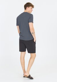 Grå T-shirt med kort ärm i kombination med svarta shorts. T-shirten har en slät yta, medan shortsen har sidofickor och en avslappnad passform.