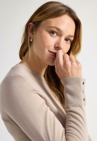 Ljusbeige l�ångärmad tröja med ribbade muddar och knappliknande detaljer. Mjukt tyg med slät textur och rund halsringning.