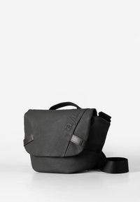 Borsa a tracolla nera in pelle con patta piegata, tracolla regolabile e branding impresso sul davanti. Texture liscia con design minimalista.