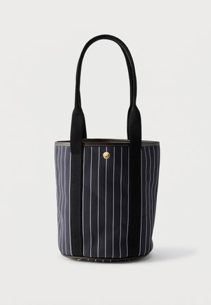 Μαύρη υφασμάτινη τσάντα tote με λεπτές κάθετες λευκές ρίγες, δύο μακριές μαύρες λαβές και μικρό στρογγυλό χρυσό κουμπί κοντά στο κέντρο πάνω μέρος.