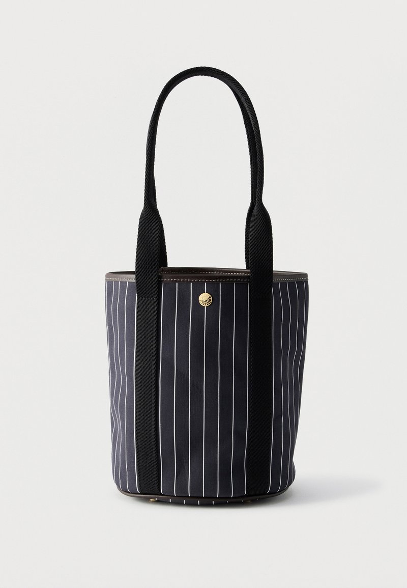 Μαύρη υφασμάτινη τσάντα tote με λεπτές κάθετες λευκές ρίγες, δύο μακριές μαύρες λαβές και μικρό στρογγυλό χρυσό κουμπί κοντά στο κέντρο πάνω μέρος.