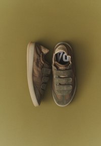 Paire de baskets vert olive avec des bandes velcro sur fond olive, montrée de côté et de dessus.