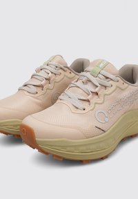 Baskets de sport rose clair avec une tige en mesh texturé, des accents verts et une semelle extérieure en caoutchouc antidérapante. Elles sont dotées de lacets et d'un logo de la marque sur le côté.