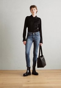 Svart langermet skjorte, blå skinny jeans, svarte ankelstøvler og en svart toteveske. Glatt stoff, slim fit og enkelt design.